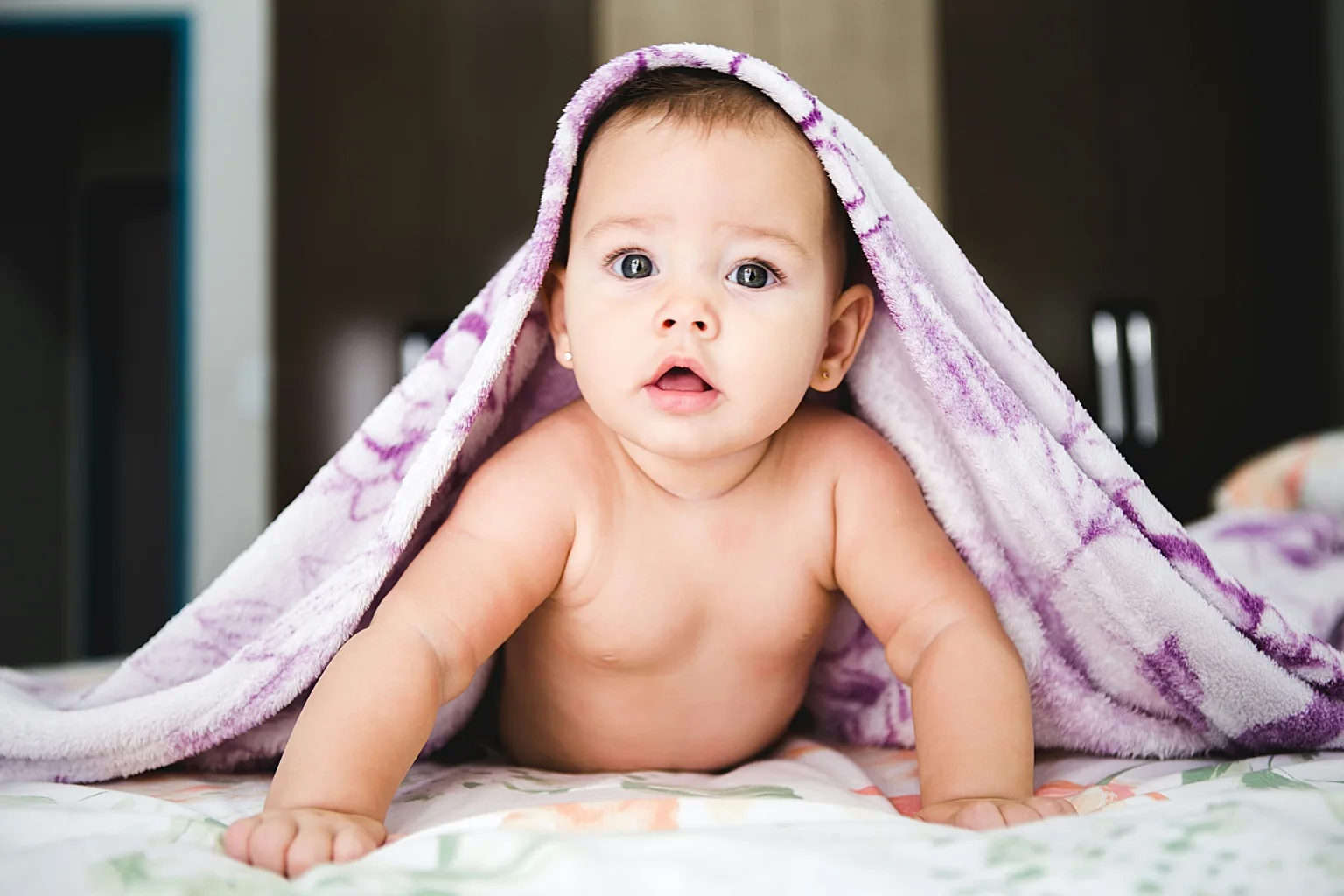 Baby onder een zachte deken als sfeerbeeld voor newborn- en babyfotografie