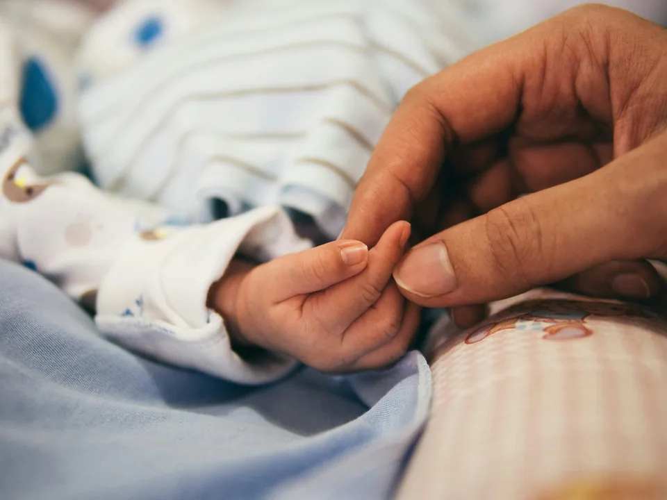 Kleine babyhand in de hand van een ouder